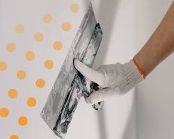 Réparation d'une fissure sur un mur de gypse avec du ruban de papier et de l'enduit.